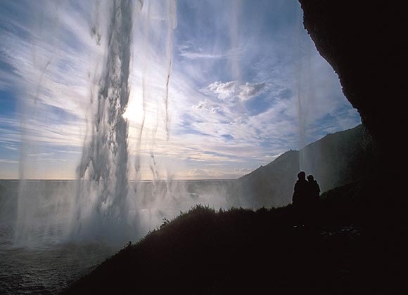 Touristen stehen unter einem Fels&uuml;berhang am Seljalandsfoss bei Seljaland im S&uuml;den Islands, aufgenommen am 28.06.2006.